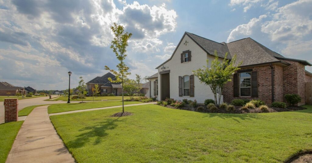 Suburban brick home Brick and white-painted suburban home with a front lawn, a sidewalk and young trees
