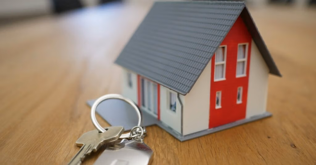 Keys and a model house House keys on a ring beside a small model house